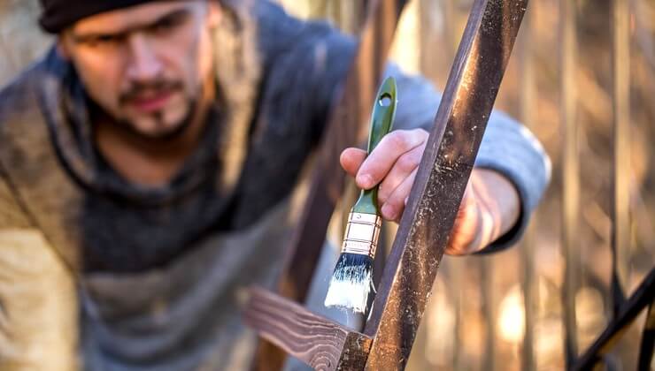 Un homme peint avec de la peinture blanche sur un escalier en bois